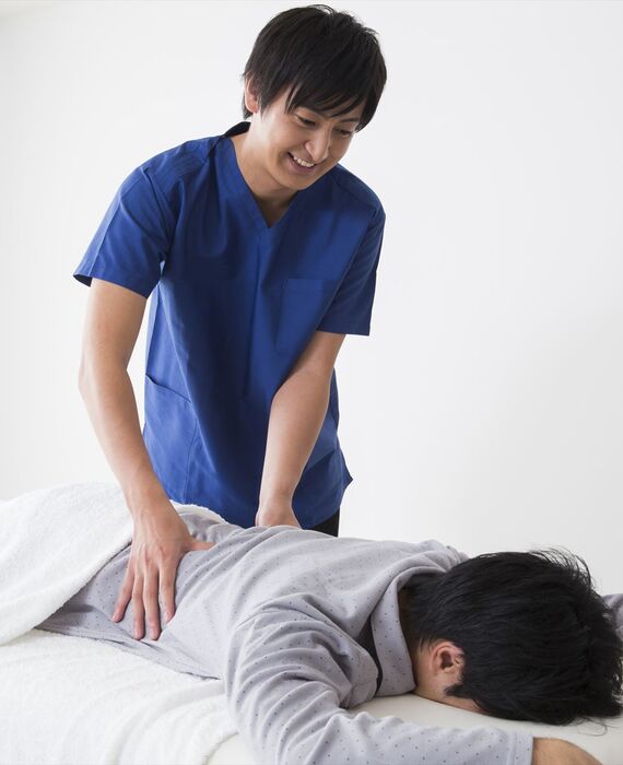 男性の腰を施術するスタッフ